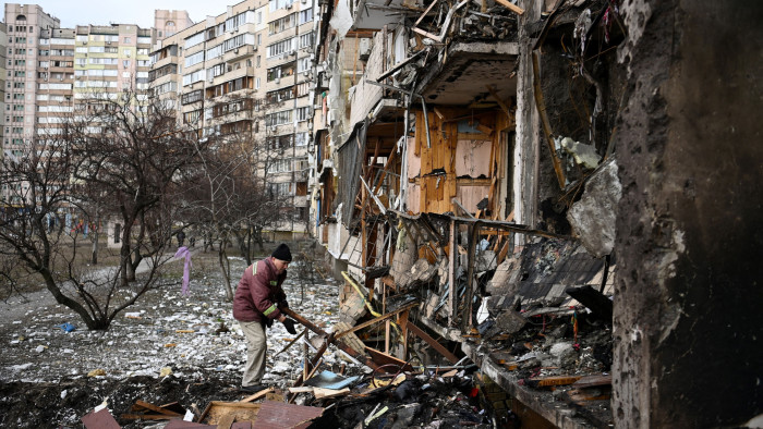 a man clears debris from a building outside of Kyiv.