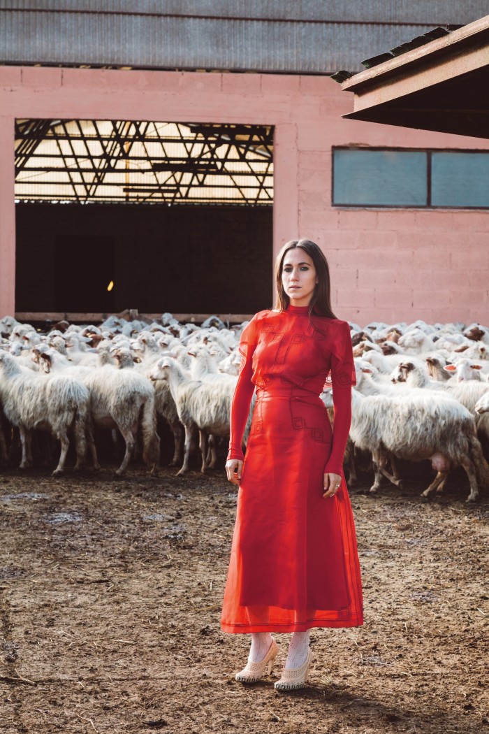 Delfina Delettrez with a flock of sheep at her family agricultural estate, I Casali del Pino, just outside Rome. She wears Fendi embroidered Byssus-silk midi dress, POA, and raffia shoes, POA, both from the spring/summer 2021 collection
