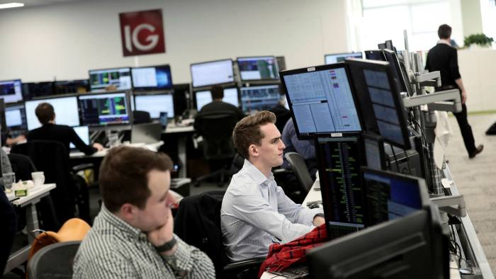 Traders look at financial information on computer screens on the IG Index trading floor in London