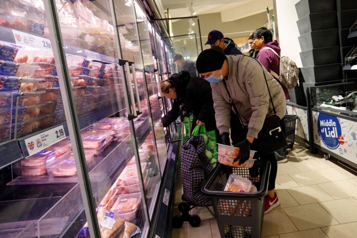 Shoppers fill their baskets with cuts of meat in a supermarket
