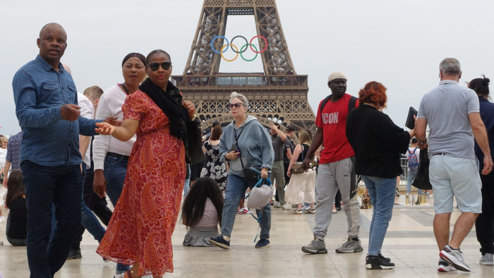 People in front of the Olympic rings on the Eiffel Tower