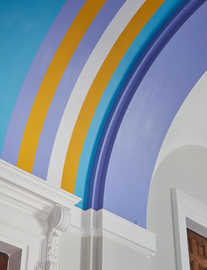 Bright coloured stripes in purple, orange and white lining the barrel vault of a ceiling