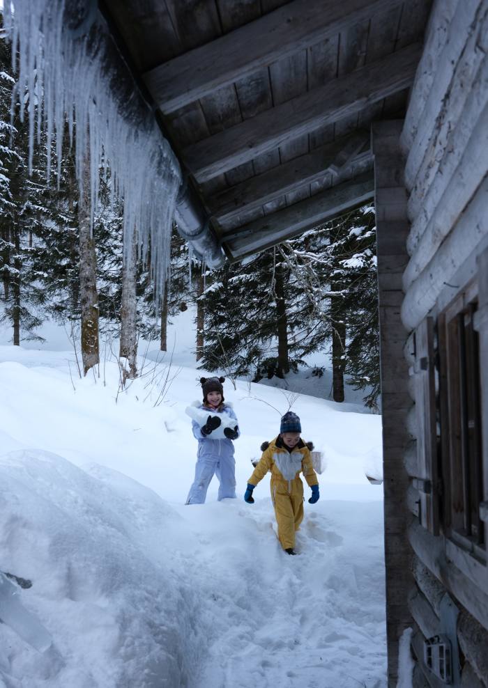 Children playing in the snow outside a cabin