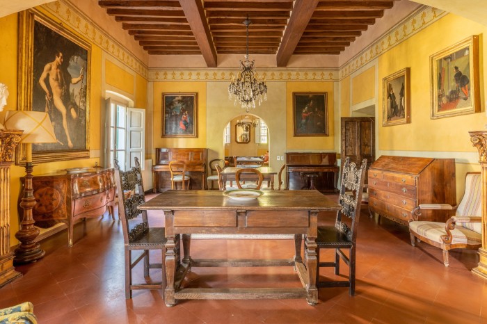 An Italianate interior includes period furniture and artwork with terracotta floor and wooden beam ceiling