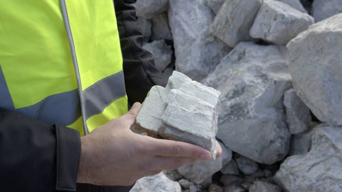 A geologist holds a rock containing spodumene, a lithium raw material