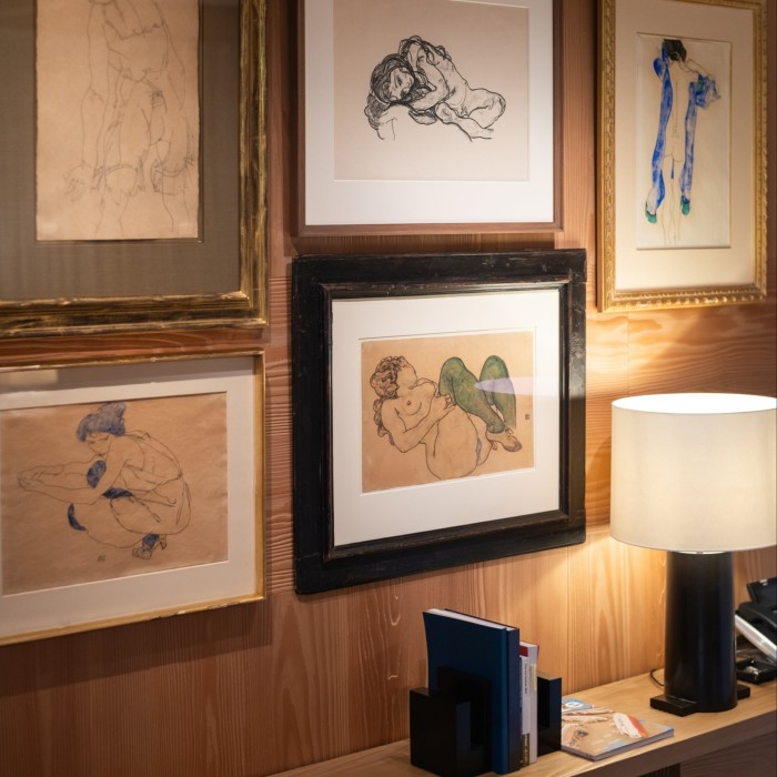 five framed artworks hanging on a wooden wall