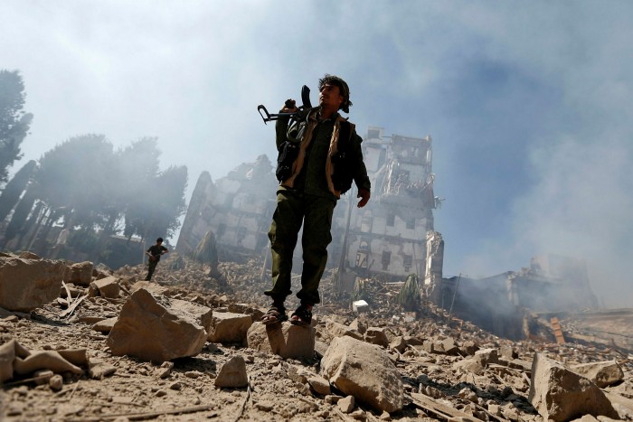 A Houthi fighter inspects the damage after a reported air strike carried out by the Saudi-led coalition targeted the presidential palace in the Yemeni capital Sanaa in December 2017