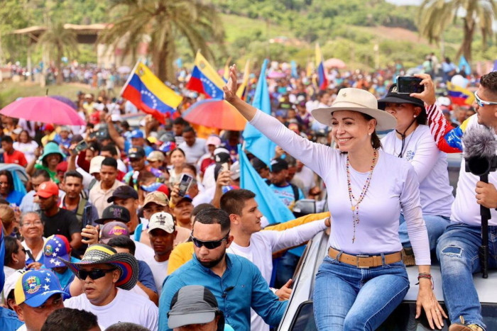 Opposition leader Machado greets supporters on top of a convoy of private vehicles during a campaign tour