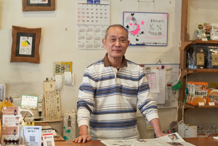 Kazuo Inoue, an elderly Japanese man standing behind a desk in his whole foods shop
