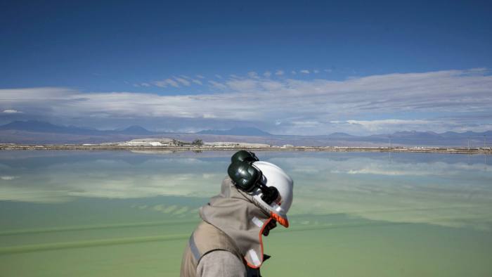 A visitor walks past a brine lake at a Sociedad Química y Minera de Chile lithium mine on the Atacama salt flat in the Atacama Desert, Chile