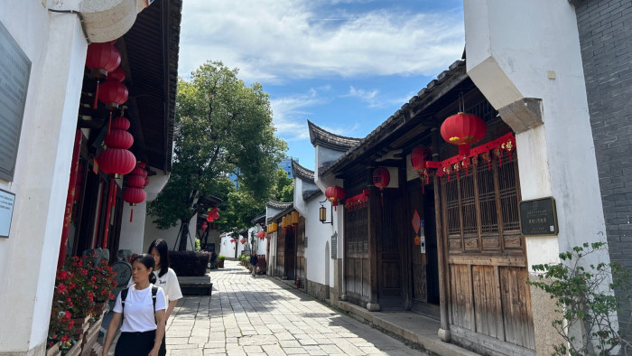 A narrow street in Fuzhou with traditional Chinese buildings and red lanterns, including the Taiwan Assembly Hall on the right