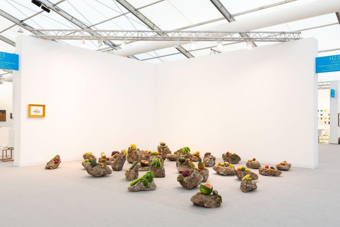 An art fair booth with 20-odd rocks on the floor and pieces of fruit on top of them