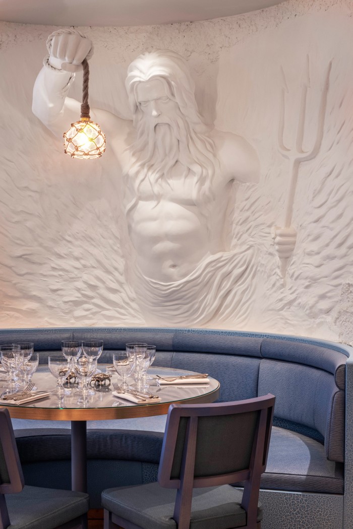 An alabaster Poseidon overlooks one of the tables on the ground floor
