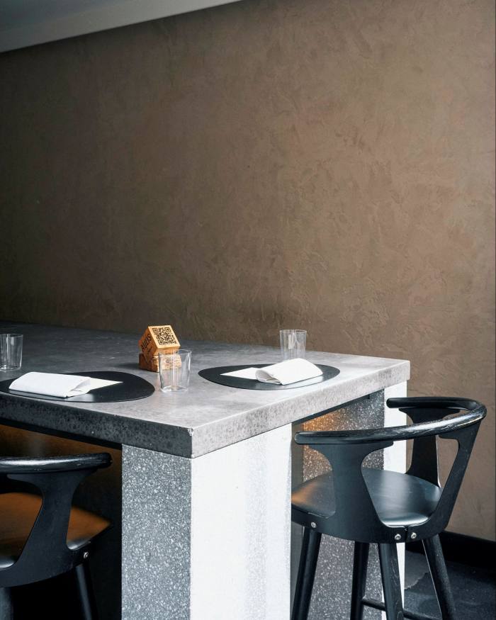 Seating at the end of a grey marble table in Aulis 