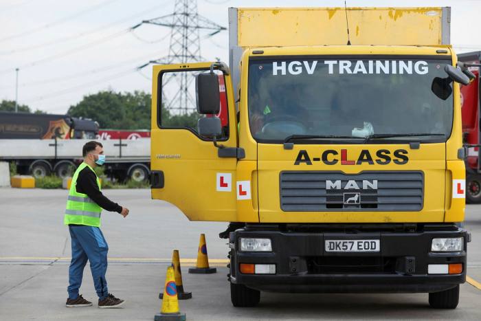 A trainee lorry driver stands next to his vehicle