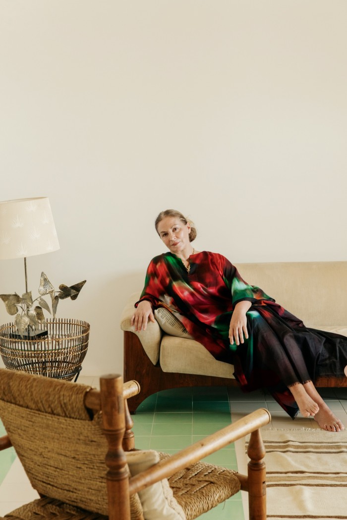 Kapoor sits on a 1970s sofa. The ’60s rattan side table and lamp are both from Alfies Antique Market. The rattan and wood chair is in the style of Charlotte Perriand