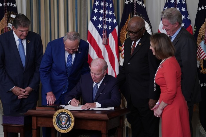 US president Joe Biden signing a document as several lawmakers looking on