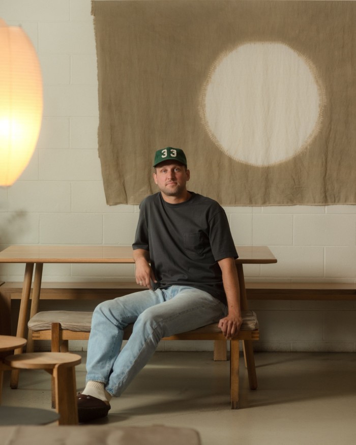 33 Acres Brewing Company president Kyle Munroe: a man in jeans, sweatshirt and baseball cap sitting on a wooden bench in the bar