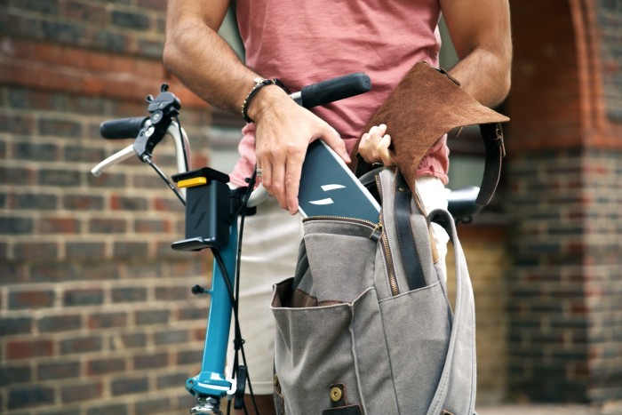 A man (seen to chest height) holding a bag while standing beside a Swytch Kit bike