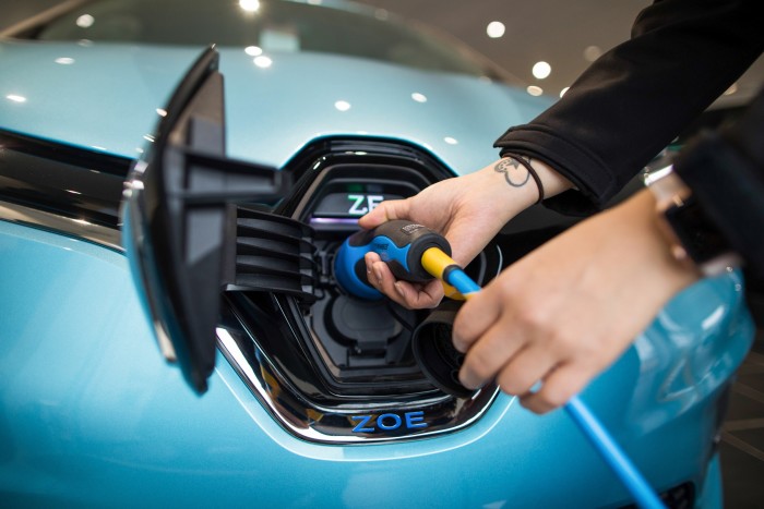 An employee places the electric charger in an electric car