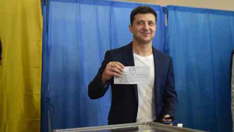 Volodymyr Zelenskyy holds his voting paper in his right hand above the ballot box as he casts his vote