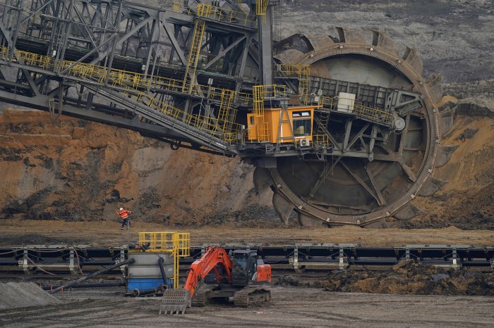 A worker throws rocks, possibly to dislodge a stuck object, at a bucket excavator removing layers of earth above the lignite coal located below, at the Welzow-Sued open-cast coal mine near Grossraschen, Germany