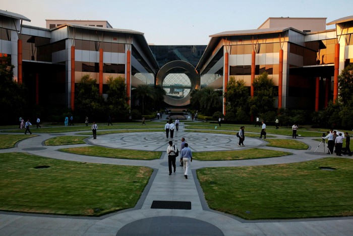 Employees walk in front of a building built by Infosys in Bangalore