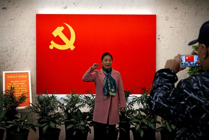 A woman poses for a photograph in front of a Communist flag at the museum of the first National Congress of the Communist Party of China in Shanghai
