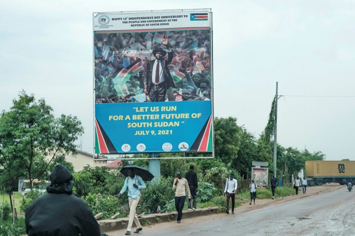 People pass a poster in Juba showing President Salva Kiir and celebrating 10 years of independence. The government of Kiir and his vice-president, Riek Machar, is racked with factionalism