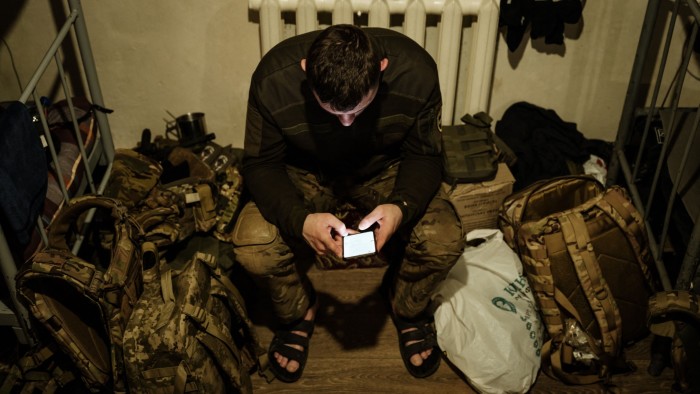 A Ukrainian serviceman uses the internet on his smartphone at a base in the Donetsk region