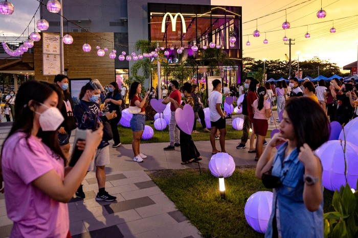 Customers take pictures next to BTS-themed decorations outside a McDonald’s restaurant during the launch of the BTS Meal in June 2021 in San Fernando, Pampanga province, the Philippines