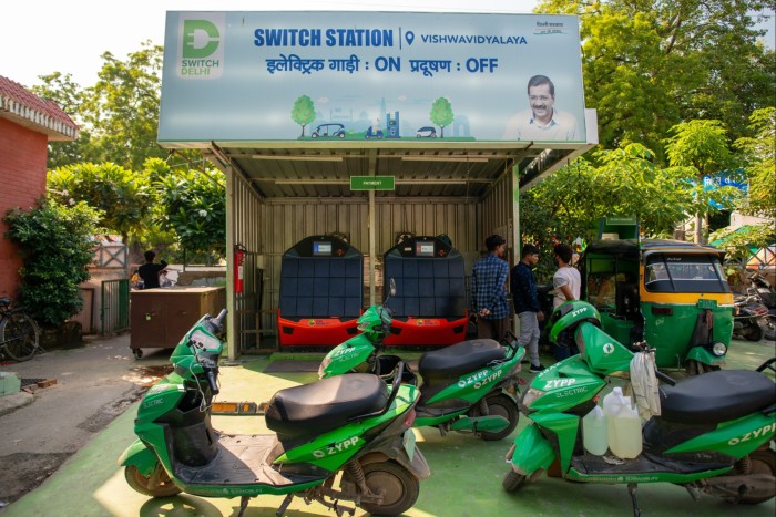 Green scooters parked at a charging station
