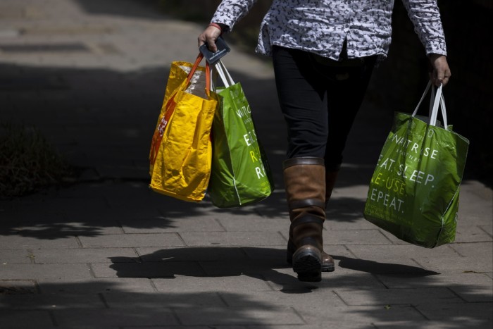 A woman walks down the street carrying Waitrose bags full of groceries