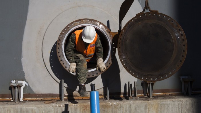 A construction worker climbs out of a fuel storage tank porthole at a VTTV oil storage terminal
