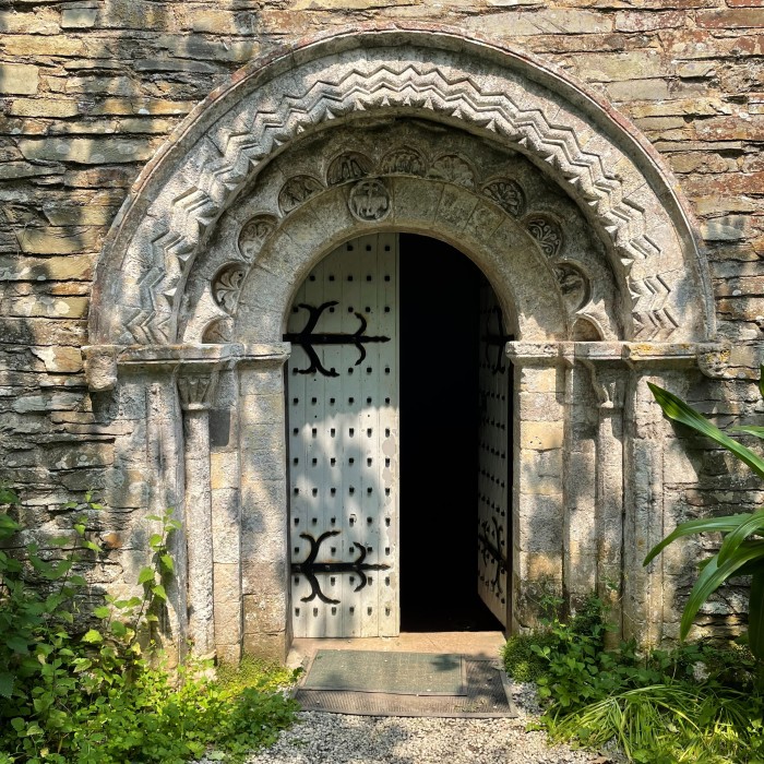 A carved stone arch and half open ancient wooden door leading into a church