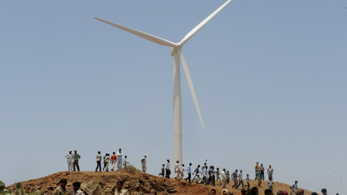 Indian villagers gather in front of a wind turbine