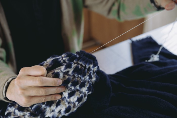 A craftsperson undoes the thread from the wool/cashmere throw