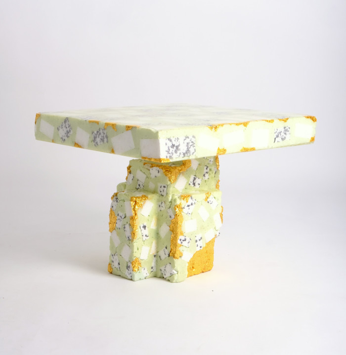 A small low table in a pale sickly green colour with golden patches