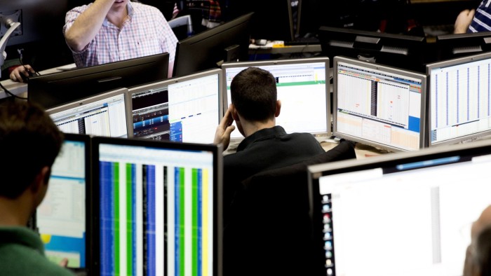 A trader looks over computer monitors as he works