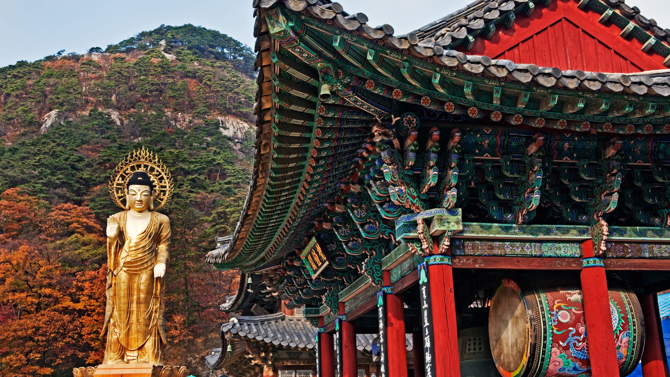 A traditionally decorated Buddhist temple with an ornate mokoshi roof carvings and a golden Buddha statue
