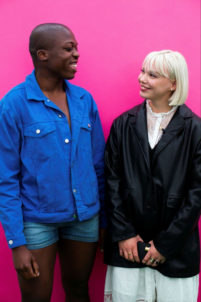 A young man in cut-off denims talks to a young woman with platinum blonde hair 