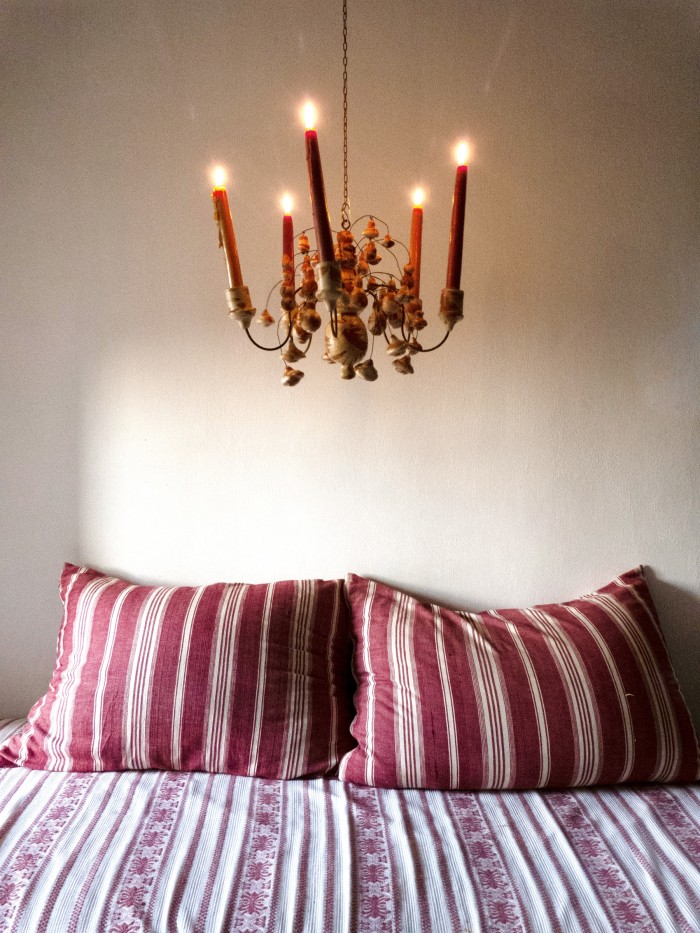 The 1690 Candili chandelier, with candles by Wax Atelier, hanging above a bed