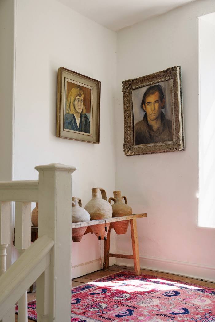 Portraits of Yasmin – by Ronald Ossory Dunlop – and Julian David, above a row of old terracotta pots