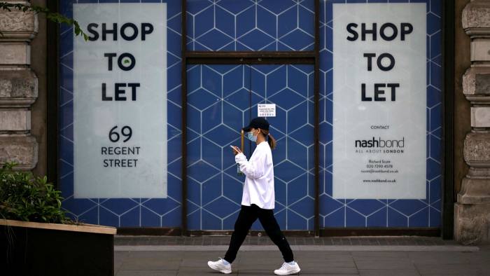 A pedestrian passes a closed-down shop in London, UK
