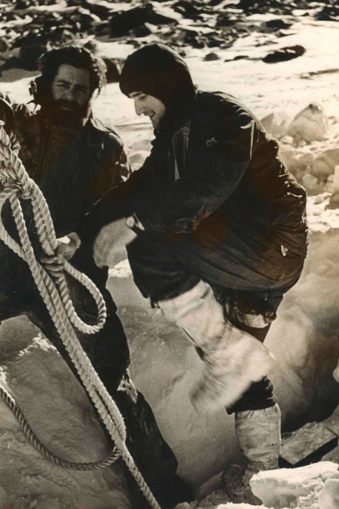 Two expedition members prepare a tow rope to pull a motor boat out of the snow
