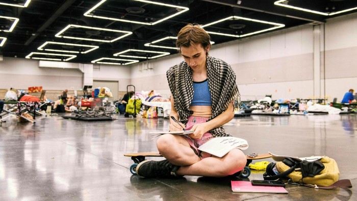 A woman writes on a notebook as people rest at the Oregon Convention Center cooling station in Portland, after a heatwave moved through the region