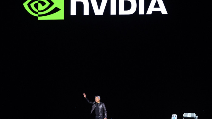 Jensen Huang speaks in front of a Nvidia logo 