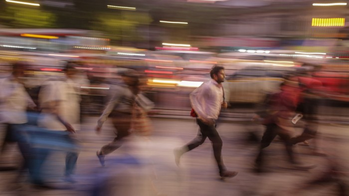 Commuters in India rushing towards a railway station - blurred to convey their motion