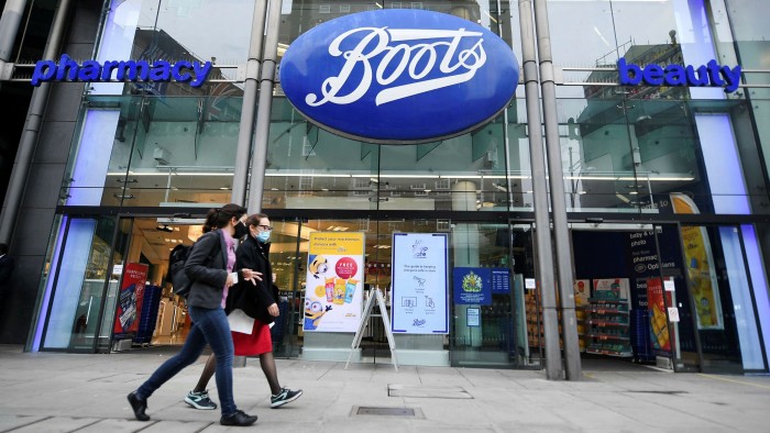 People walk past a Boots store