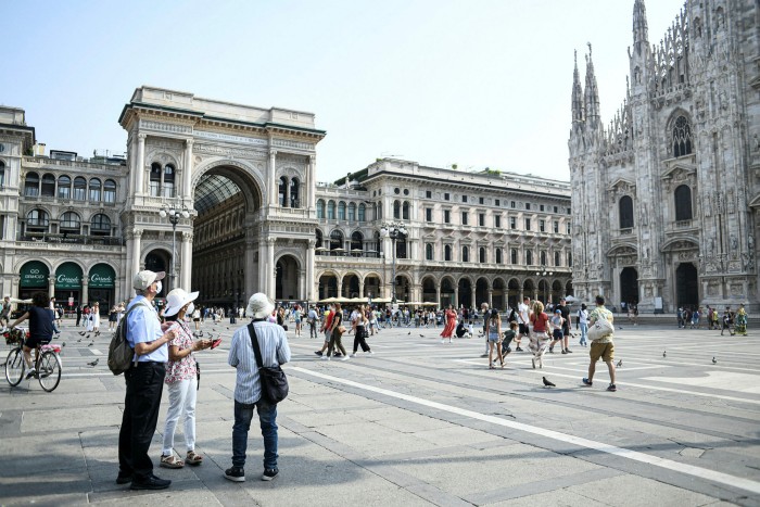 Tourists wearing protective masks looking at the Duomo Cathedral in Milan, Italy